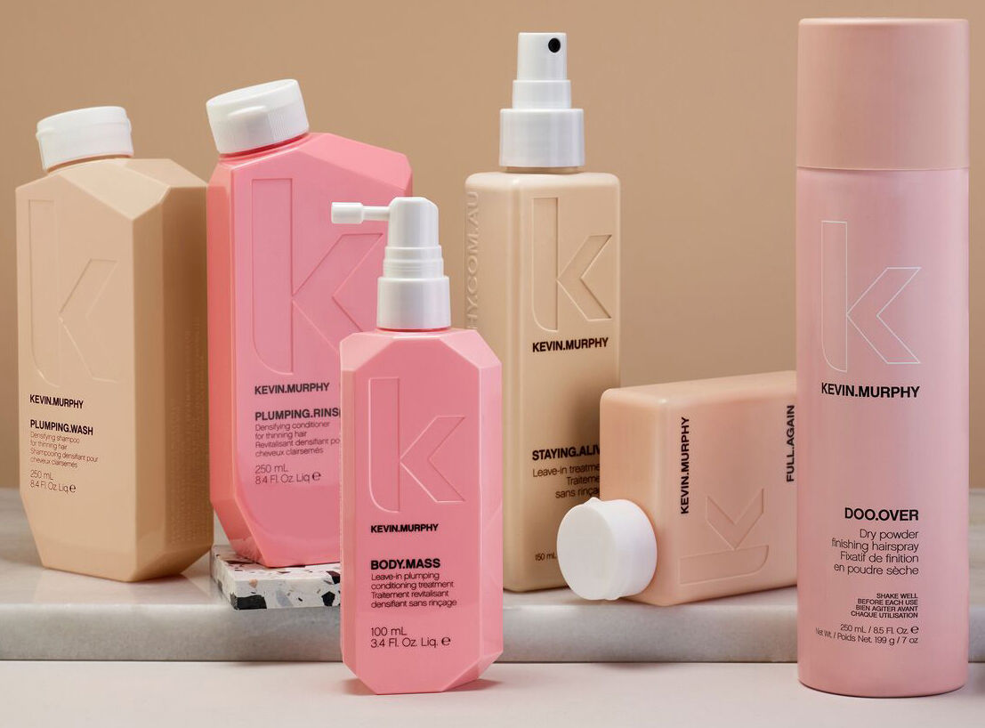 A range of Kevin Murphy hair care products in soft pink and beige packaging against a peach background